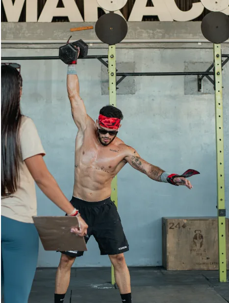 Atleta con una mancuerna arriba mientras una jueza cuenta repeticiones